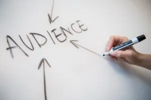 Hand drawing the word Audience with arrows pointing to it on a whiteboard