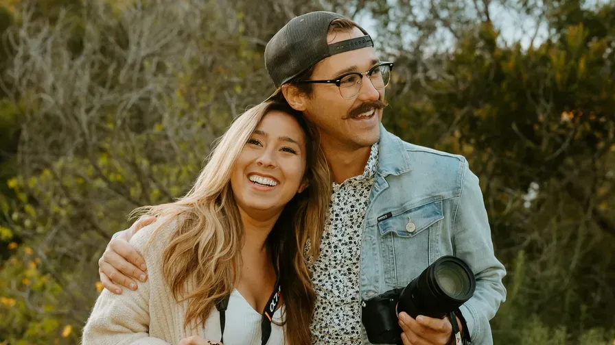 Two creators smiling outdoors, one holding a DSLR camera